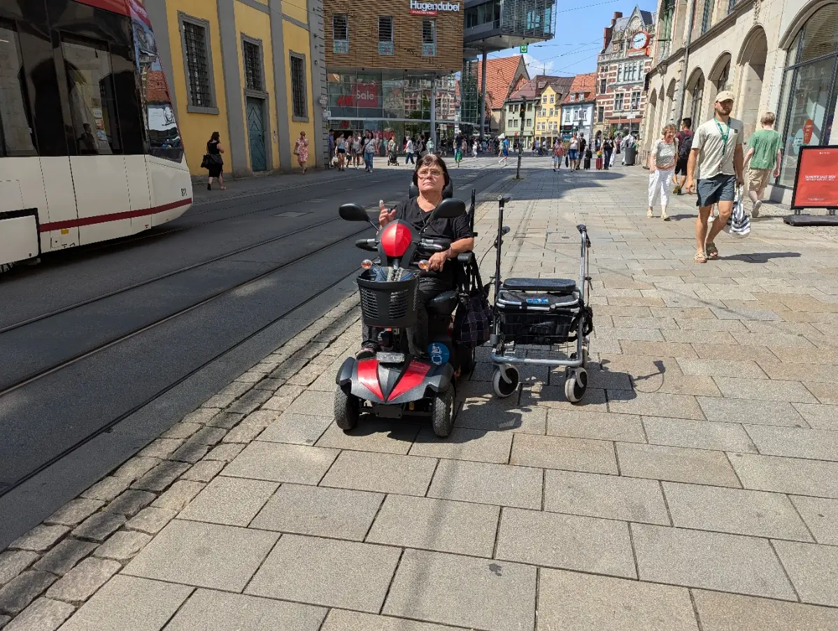 Petra sitzt auf Ihrem Senioren-Mobil. Daneben steht Timo-Thejus sein Rollator.