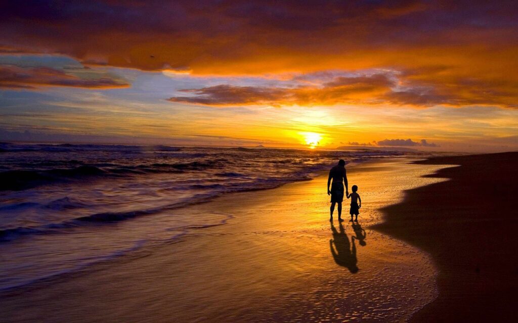 Vater und Sohn am Strand bei Sonnenuntergang